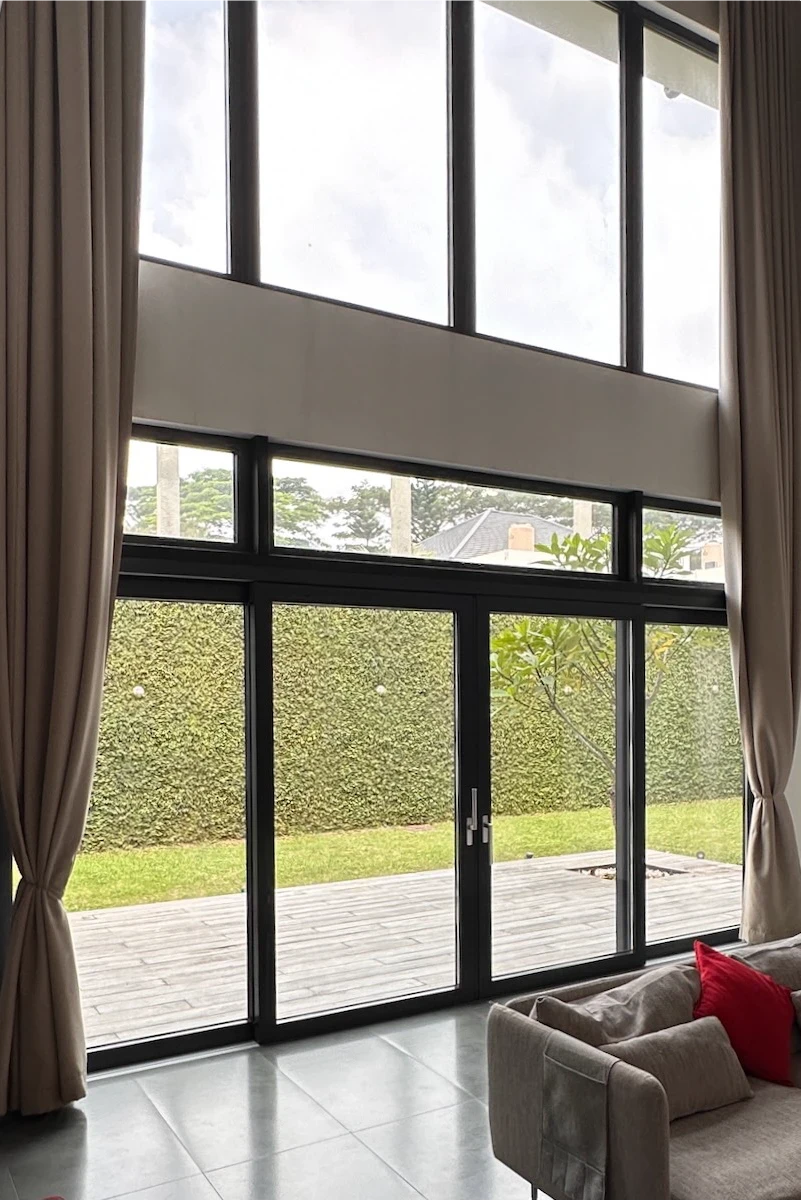 A pair of closed, UPVC double doors in wood decor with a vertical metal handle, set in a stone wall entrance. Smooth stones line the threshold and textured stone surrounds the doorway.